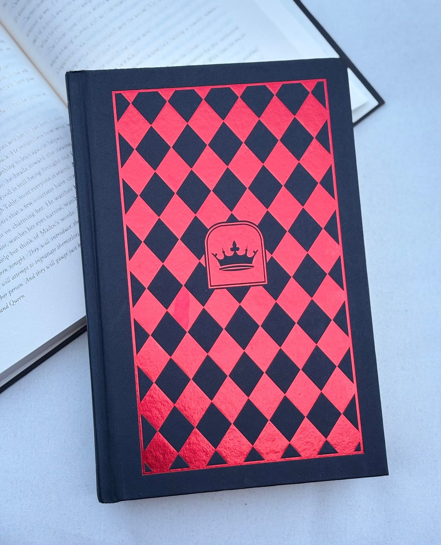 Book with red and black checkered cover and emblem on a light blue background