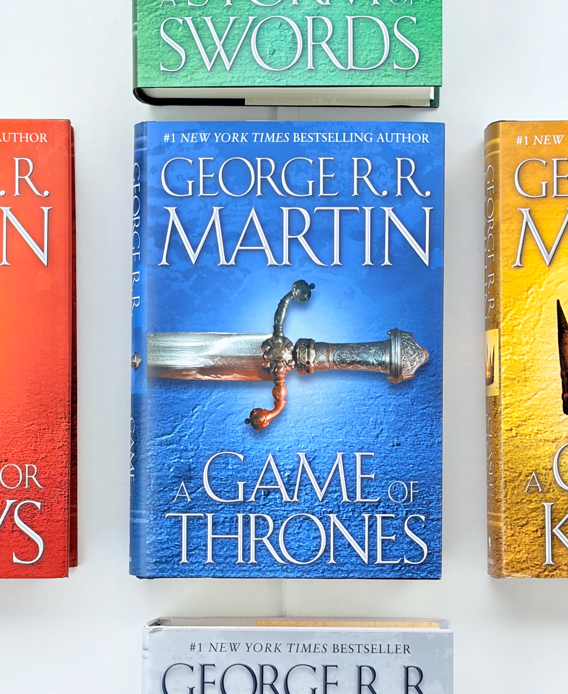 Four books from the 'A Game of Thrones' series by George R.R. Martin on a white background.